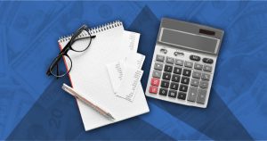 Financial planning essentials: calculator, notebook, pen, and receipts arranged on a US currency pattern background, symbolizing preparation for a financial emergency kit to reduce stress in uncertain times.